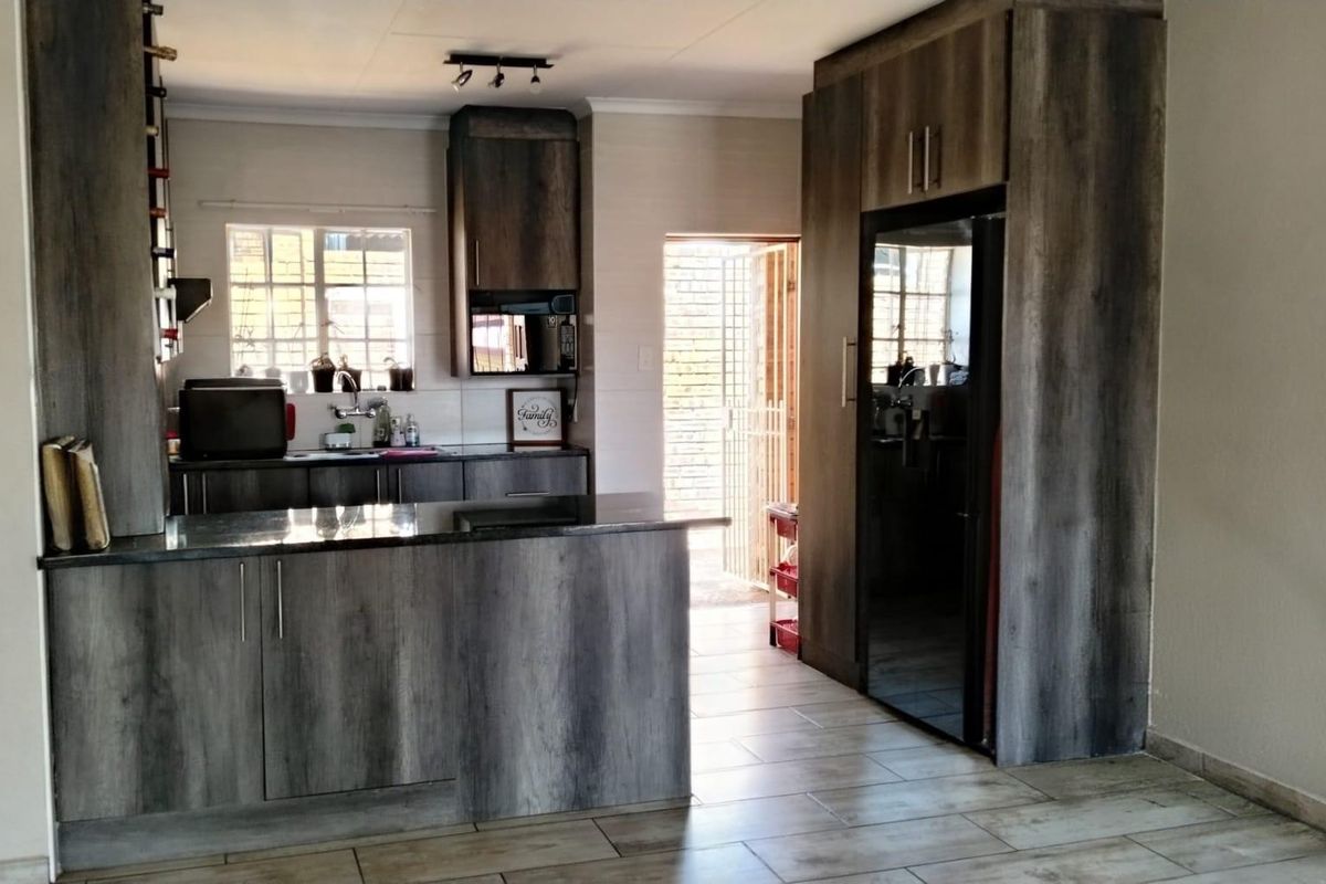 Modern kitchen featuring dark wood-grain cabinetry, granite countertops, and tiled flooring, with direct access to an exterior security gate.