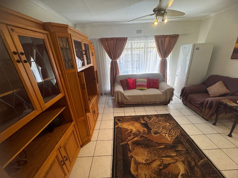 A living room featuring tiled flooring and a ceiling fan, providing a functional space with natural light through the window.