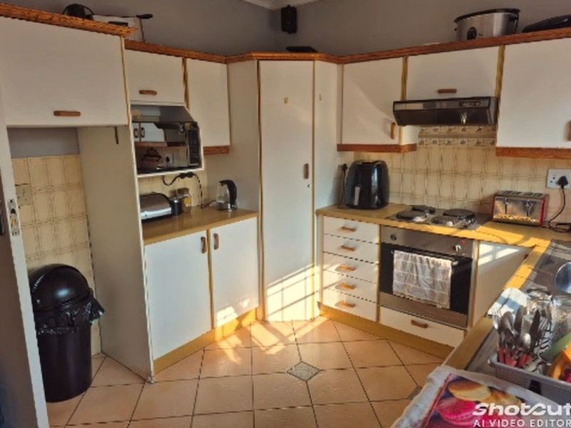 A functional kitchen featuring white cabinetry with wood trim, tiled backsplash, built-in oven, gas hob, and tiled flooring.