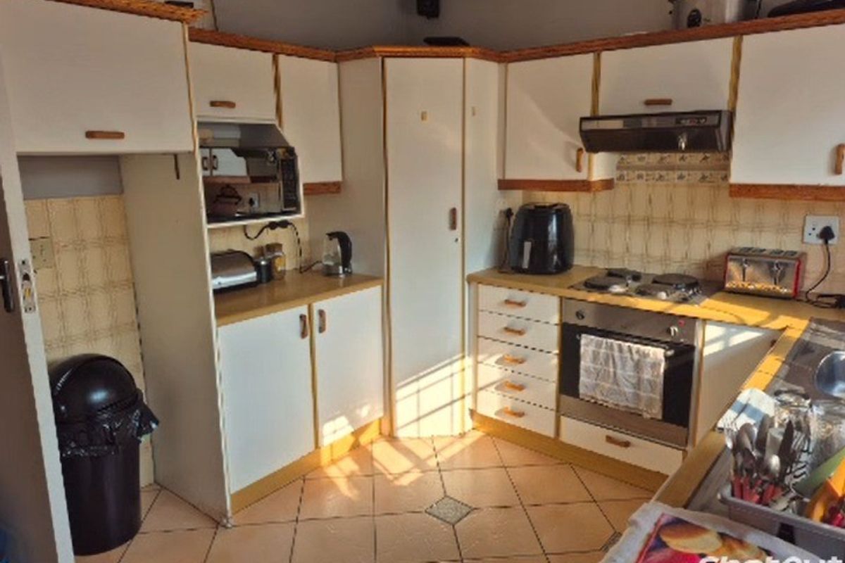A functional kitchen featuring white cabinetry with wood trim, tiled backsplash, built-in oven, gas hob, and tiled flooring.