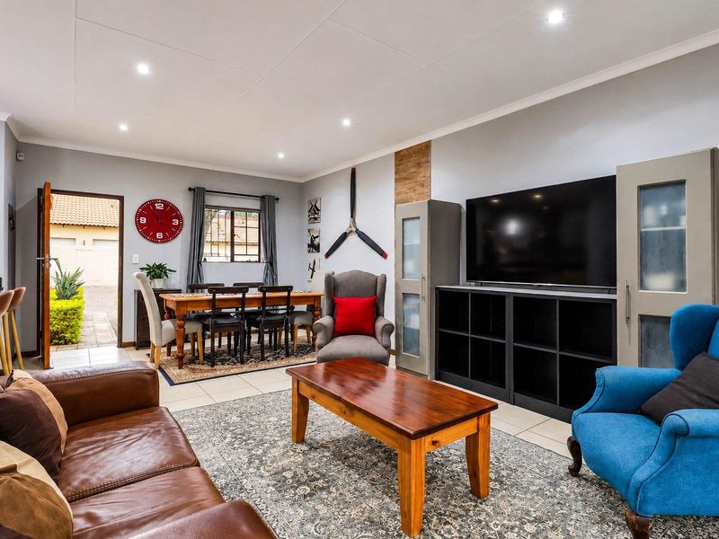 An open-plan living and dining area featuring tiled flooring, recessed downlighting, and direct access to an outdoor patio space.