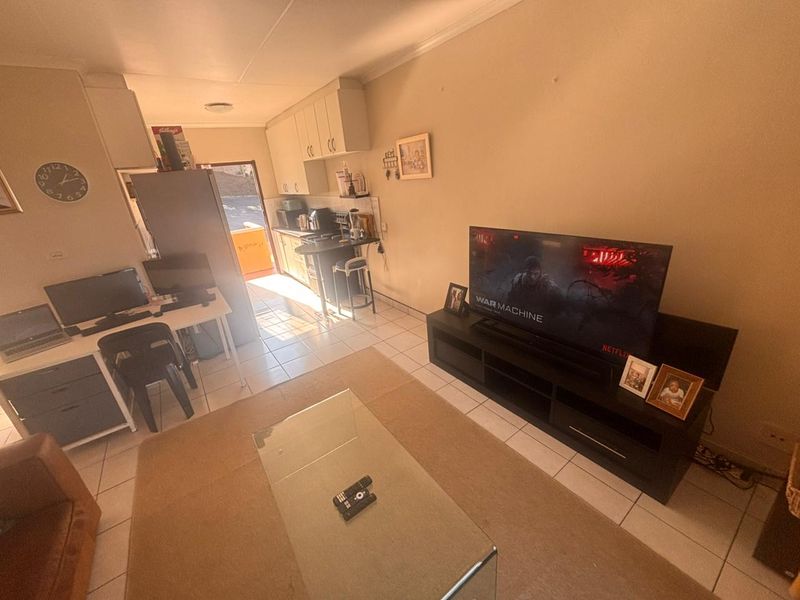 Open-plan living area featuring tiled flooring and a compact kitchen with built-in cabinetry, providing a functional layout for daily living.
