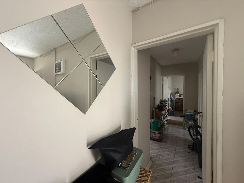 A narrow interior hallway featuring tiled flooring and visible surface-mounted electrical wiring, connecting multiple rooms within the townhouse.