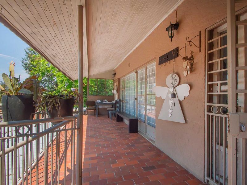 A covered outdoor patio featuring terracotta tiled flooring, a timber-clad ceiling, and sliding glass door access to the main living area.