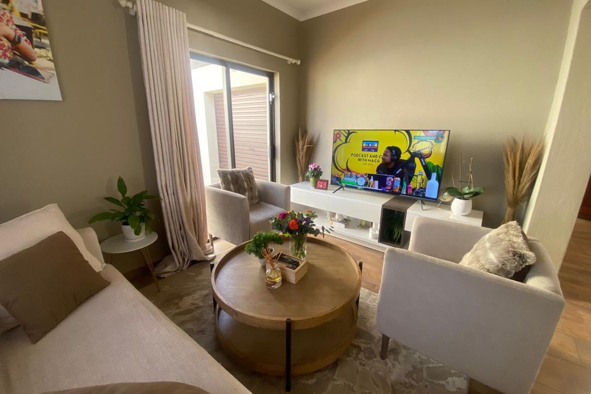 A cozy living room featuring neutral wall tones, tiled flooring, and a sliding glass door providing natural light and access to the exterior.
