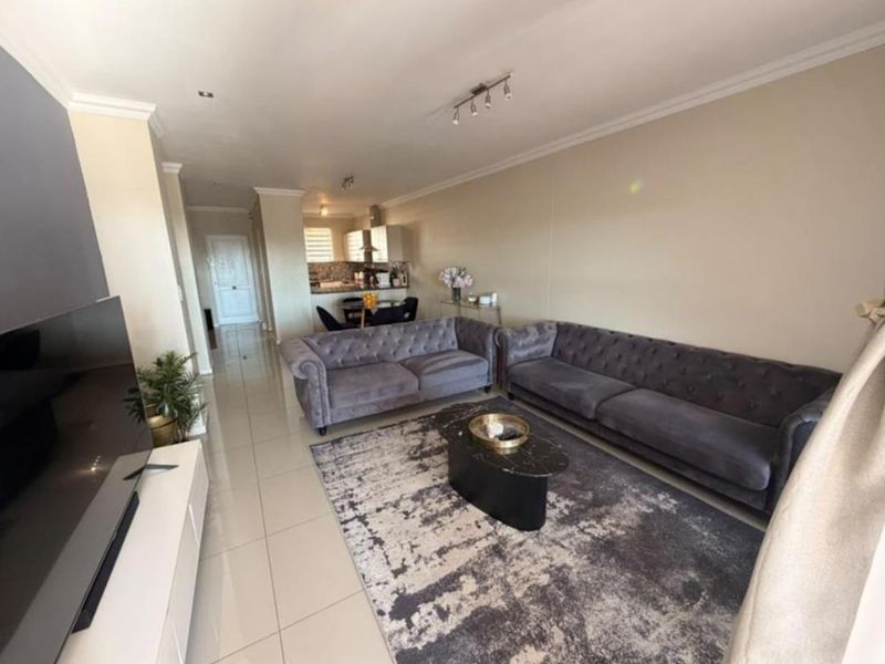 Spacious open-plan living area featuring polished tile flooring, neutral walls, and a seamless transition into a functional kitchen space.