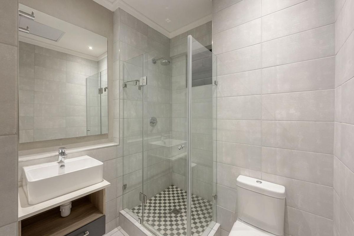 Modern bathroom featuring a vessel sink vanity, glass-enclosed shower with mosaic tiling, and a clean, neutral tile finish throughout.