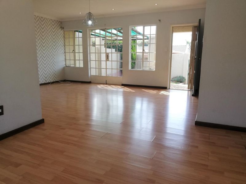 Spacious, empty living area featuring laminate flooring, recessed lighting, and direct access to the rear patio through glass-paned french doors.