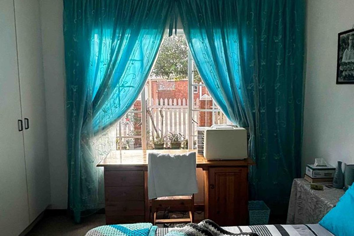 A bedroom featuring built-in cupboards and a window with natural light, providing a functional space for rest or study.