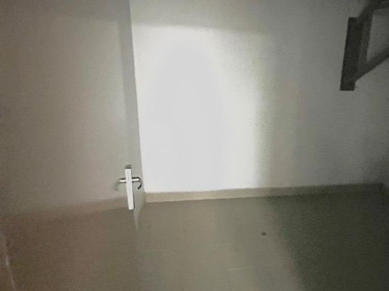 A basic, empty utility space featuring tiled flooring and an exposed corrugated metal ceiling, suitable for storage or functional use.