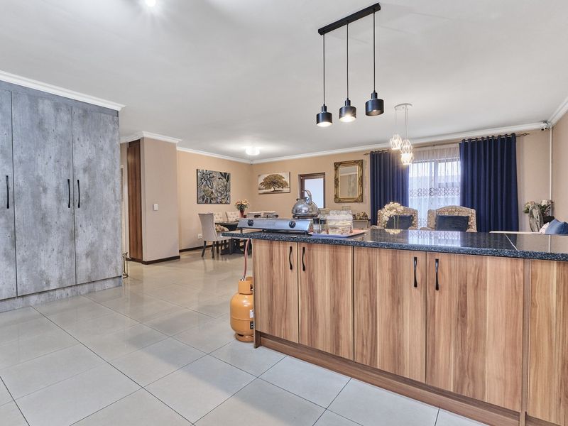 Spacious open-plan living and kitchen area featuring a central island with granite countertops, modern cabinetry, and tiled flooring throughout.
