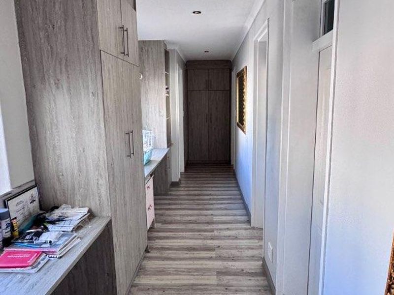 A functional hallway featuring built-in cabinetry, integrated desk space, and durable wood-look flooring, providing efficient storage and workspace solutions.