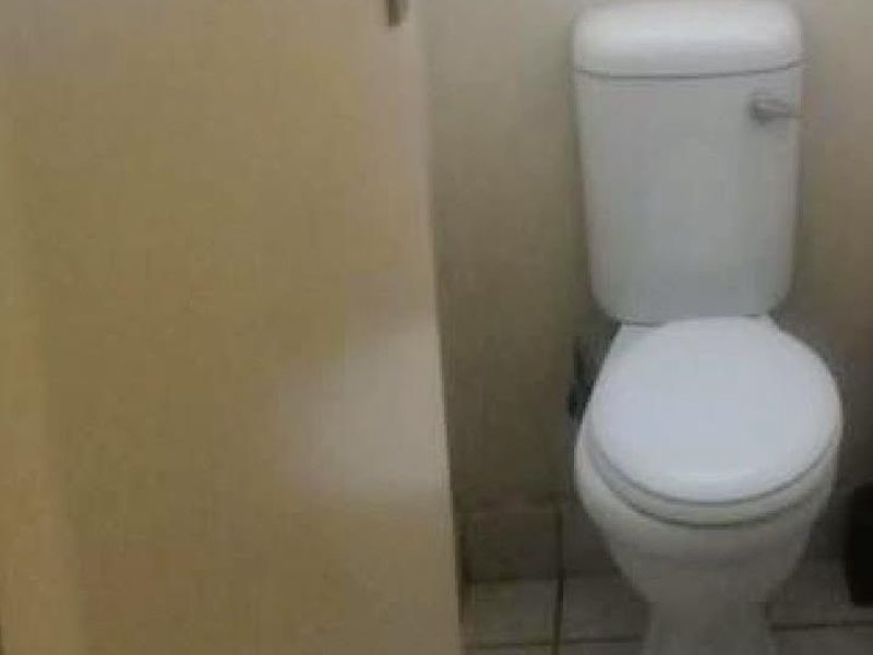 A compact bathroom featuring a standard toilet and tiled flooring, requiring cosmetic updates to improve its overall condition.