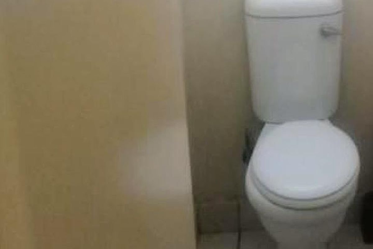 A compact bathroom featuring a standard toilet and tiled flooring, requiring cosmetic updates to improve its overall condition.