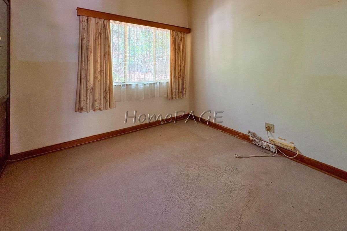 A vacant bedroom featuring neutral walls, carpeted flooring, and a window with built-in curtain rails.
