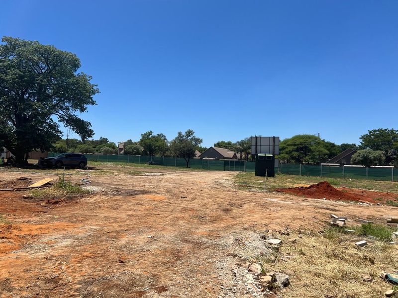 A large, undeveloped plot of land featuring natural vegetation, mature trees, and perimeter fencing, offering a blank canvas for future residential development.