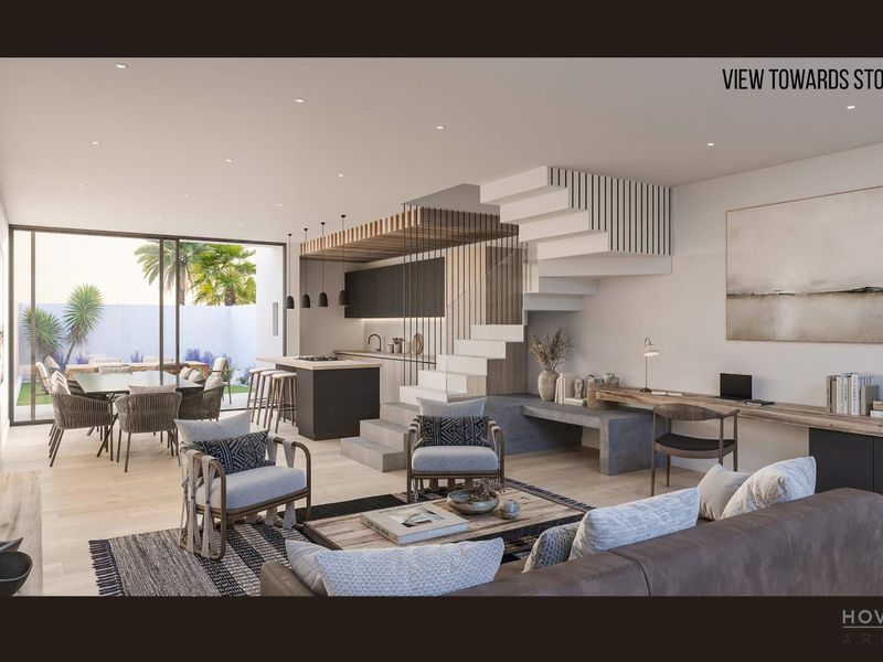 Modern open-plan living area featuring a sleek kitchen, integrated staircase, and seamless flow to the outdoor patio and garden through large sliding doors.