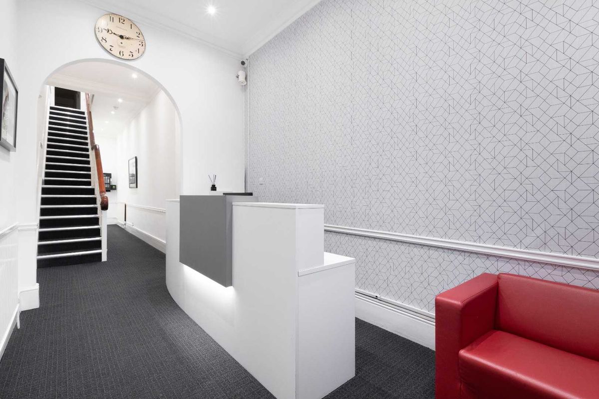 Professional office reception area featuring a modern reception desk, arched entryway, and staircase leading to upper levels.