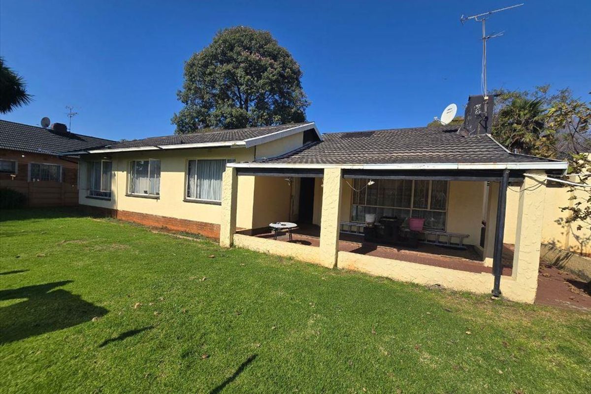 Rear view of the house featuring a covered patio area, tiled roof, and a spacious garden.