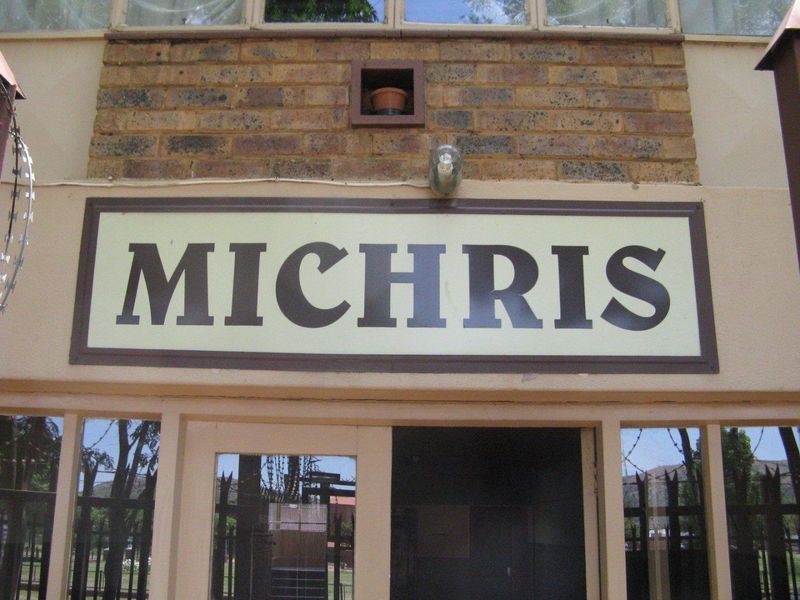 Front facade of the apartment building featuring brickwork, security fencing, and building signage.