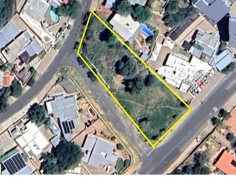 An aerial view of a vacant commercial corner plot situated in a developed urban area.