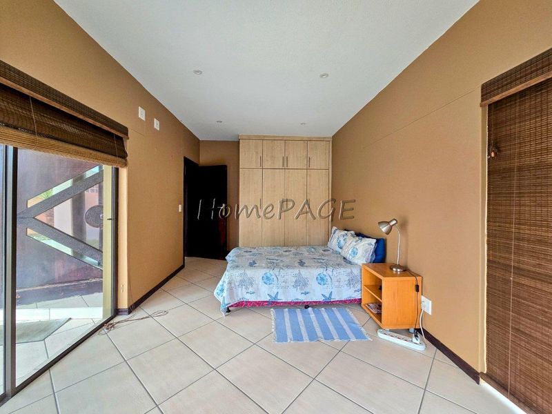 A bedroom featuring tiled flooring, built-in cupboards, and a sliding glass door providing access to the exterior.