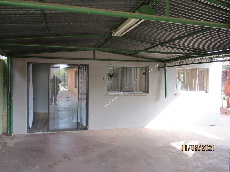 Covered outdoor patio area featuring a corrugated metal roof, concrete flooring, and access to the interior via a sliding glass door.