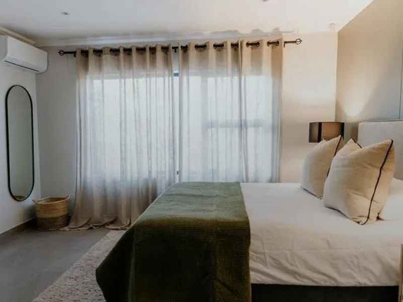A well-maintained bedroom featuring tiled flooring, recessed lighting, and a wall-mounted air conditioning unit.
