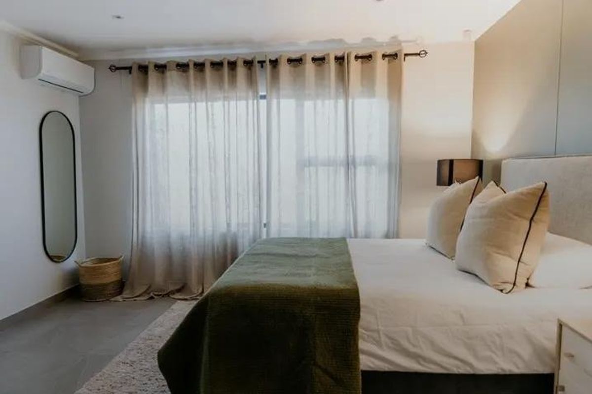 A well-maintained bedroom featuring tiled flooring, recessed lighting, and a wall-mounted air conditioning unit.