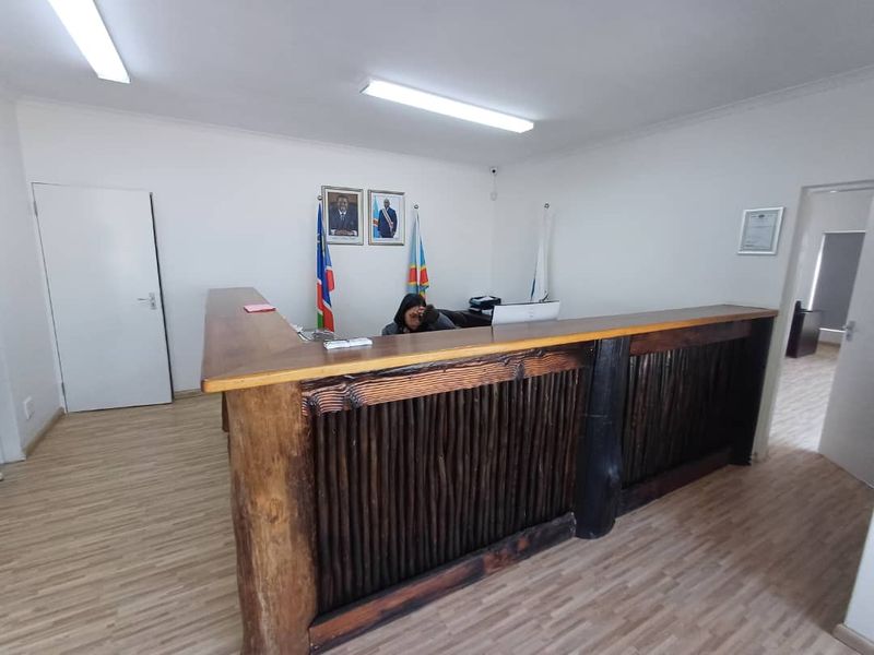 A professional office space featuring a rustic built-in wooden reception desk, laminate flooring, and bright overhead fluorescent lighting.