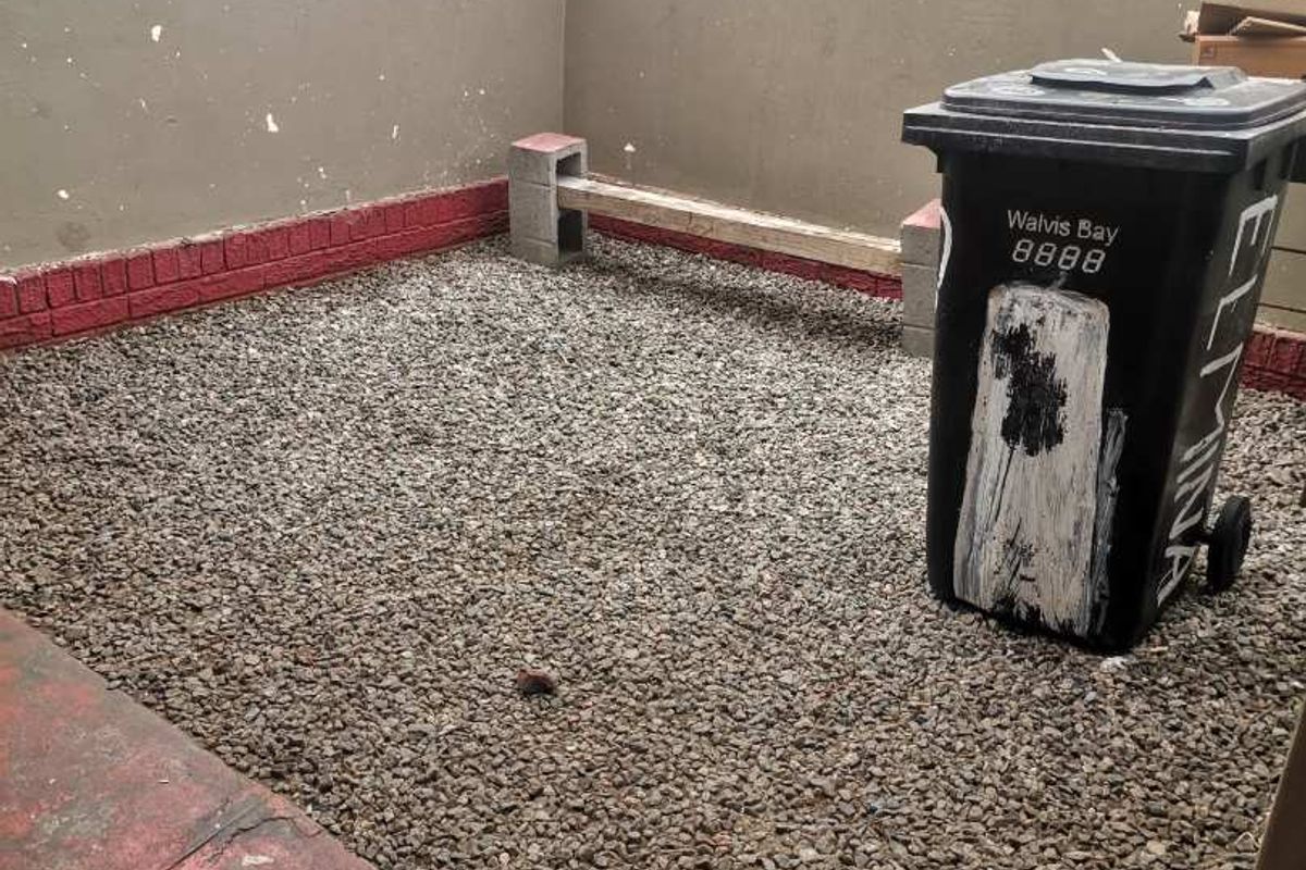 A small, low-maintenance rear courtyard area featuring a gravel surface and perimeter boundary walls.