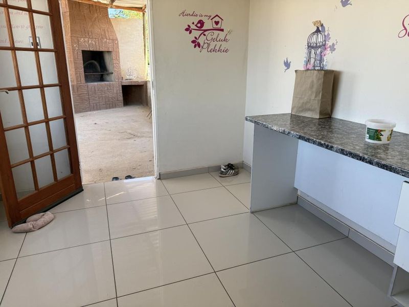 Covered patio area featuring tiled flooring, a built-in counter, and an outdoor built-in braai, providing a functional space for outdoor entertaining.