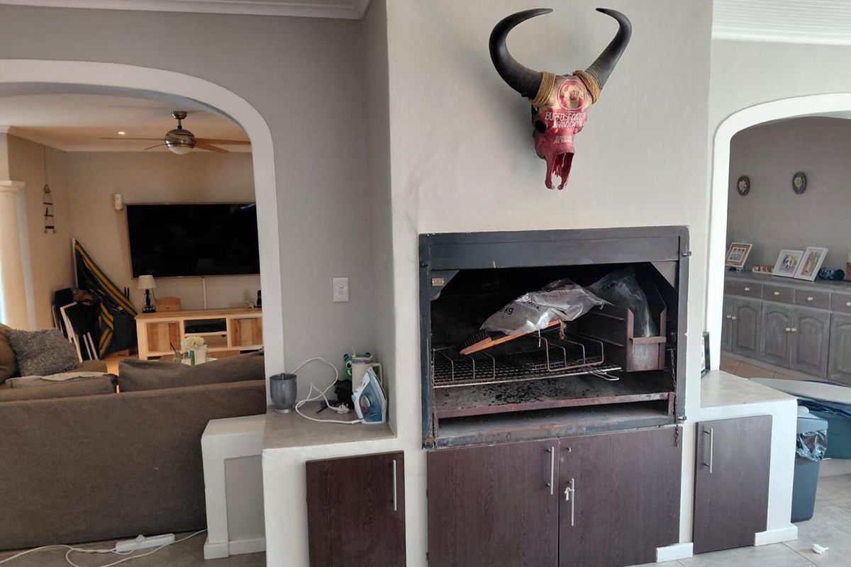 Living area featuring a built-in indoor braai, tiled flooring, and arched transitions to adjacent spaces.