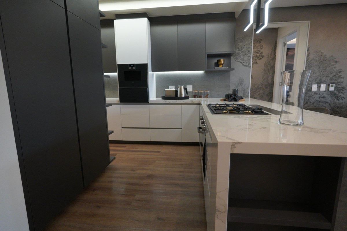 Modern kitchen featuring a central island with a built-in gas hob, sleek two-tone cabinetry, stone countertops, and integrated oven.