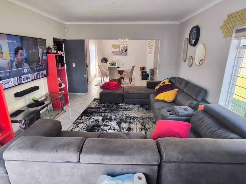 Spacious open-plan living area featuring tiled flooring, large windows for natural light, and a seamless flow into the adjacent dining space.