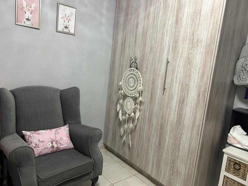 A bedroom featuring a large, wood-grain finish built-in wardrobe and neutral tiled flooring.