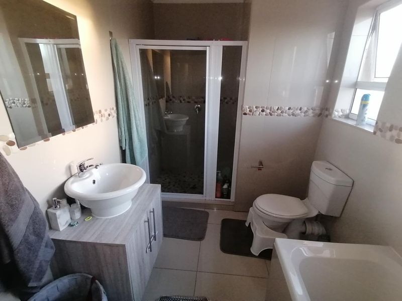 A functional bathroom featuring a vanity with a vessel sink, a separate shower enclosure, and a standard toilet with tiled finishes.