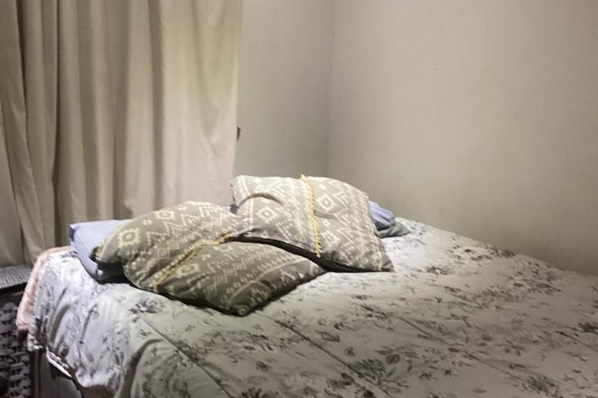 A standard bedroom featuring laminate flooring and crown molding, providing a functional and comfortable sleeping space.