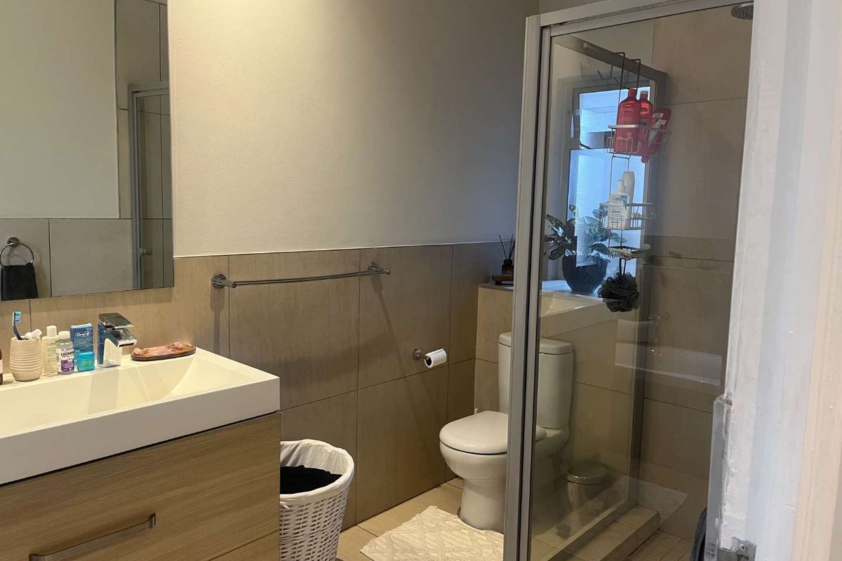A modern bathroom featuring a vanity with basin, a glass-enclosed shower, and neutral wall tiling.