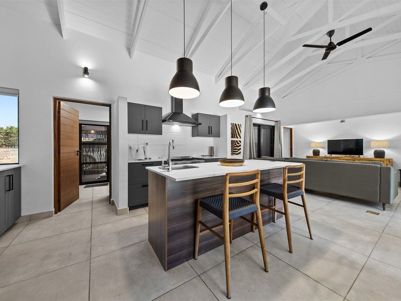 Modern open-plan living area featuring a sleek kitchen with a central island, vaulted ceilings, and contemporary finishes throughout.