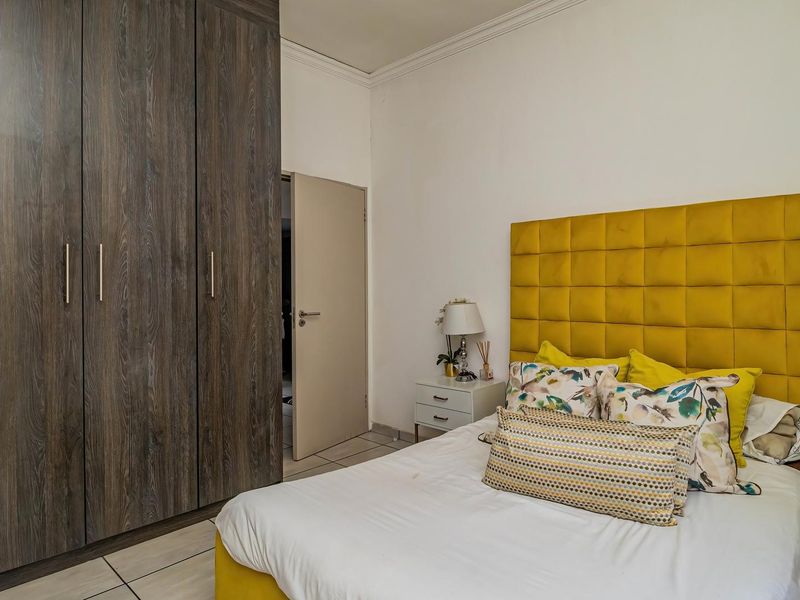 A well-maintained bedroom featuring dark wood-grain built-in cupboards, tiled flooring, and decorative ceiling cornicing.