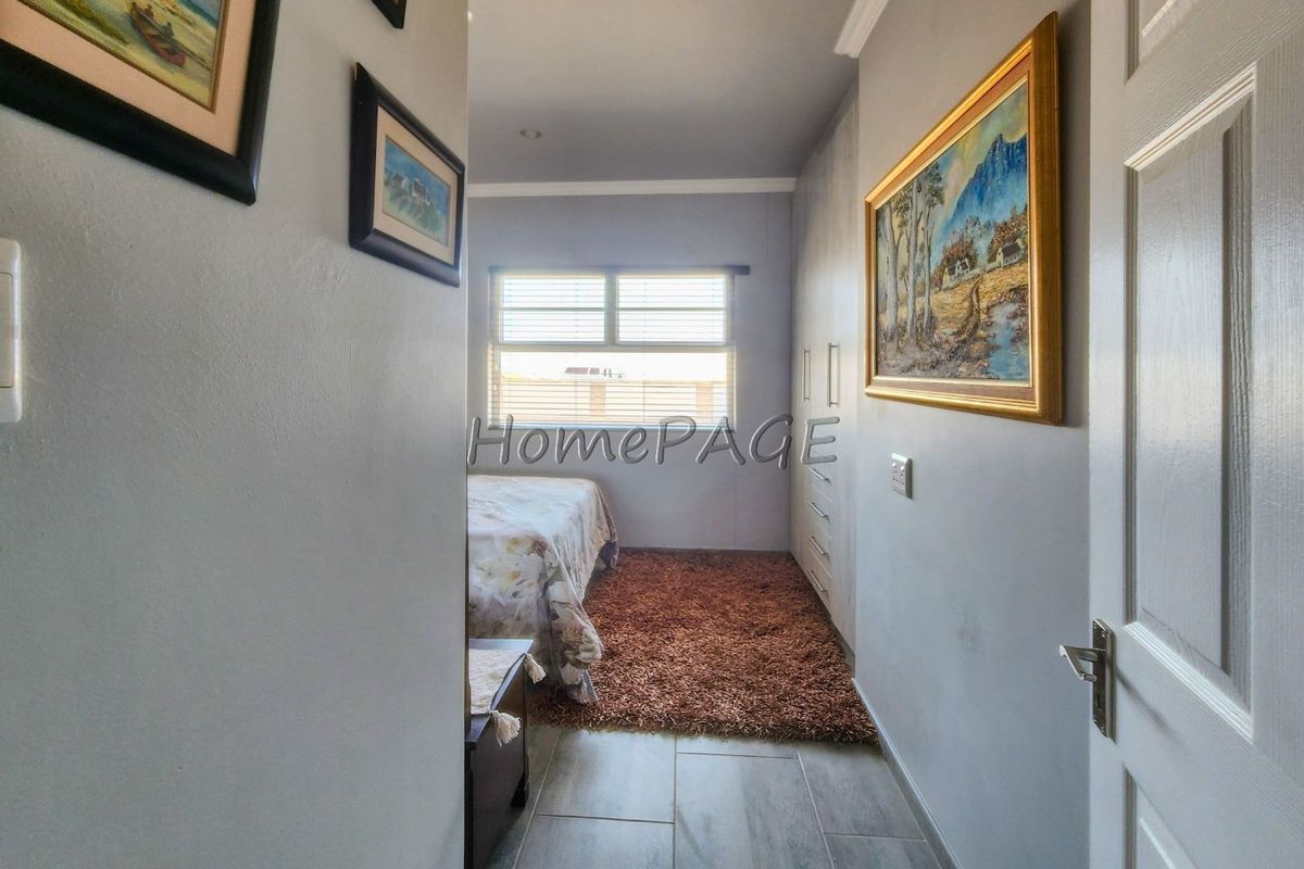 A bedroom featuring built-in cupboards, tiled flooring, and a window with blinds, offering a clean and functional living space.