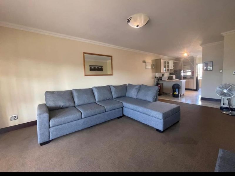 Open-plan living area featuring carpeted flooring and a connected kitchen space with built-in cabinetry and counter area.