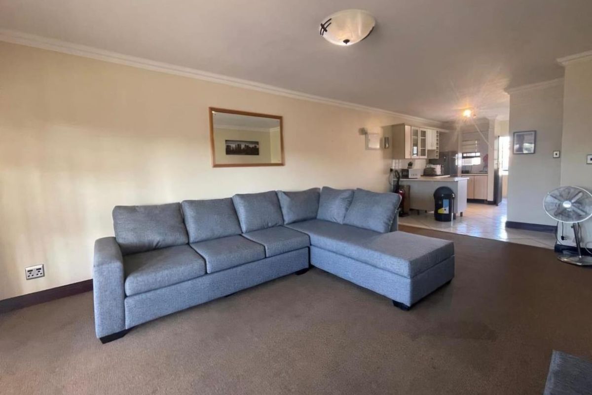 Open-plan living area featuring carpeted flooring and a connected kitchen space with built-in cabinetry and counter area.