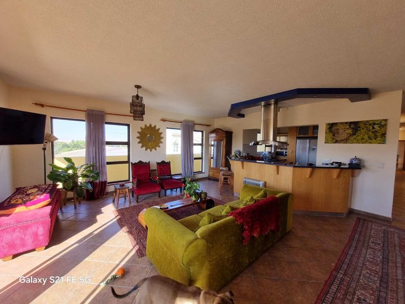 Spacious open-plan living area featuring a kitchen with a breakfast bar, stainless steel extractor fan, and tiled flooring throughout.