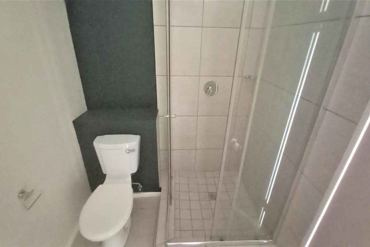 A modern bathroom featuring a glass-enclosed shower with tiled walls and a standard toilet.