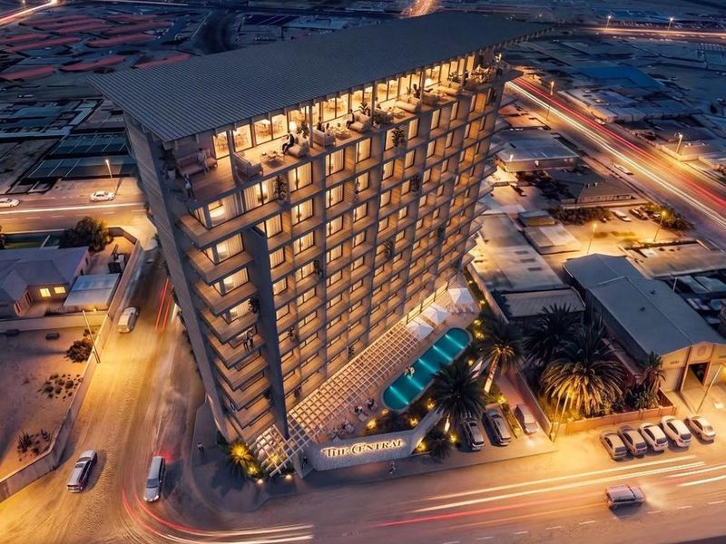 Aerial night view of The Central hotel building, featuring a swimming pool, multiple balconies, and a rooftop terrace in a modern urban setting.