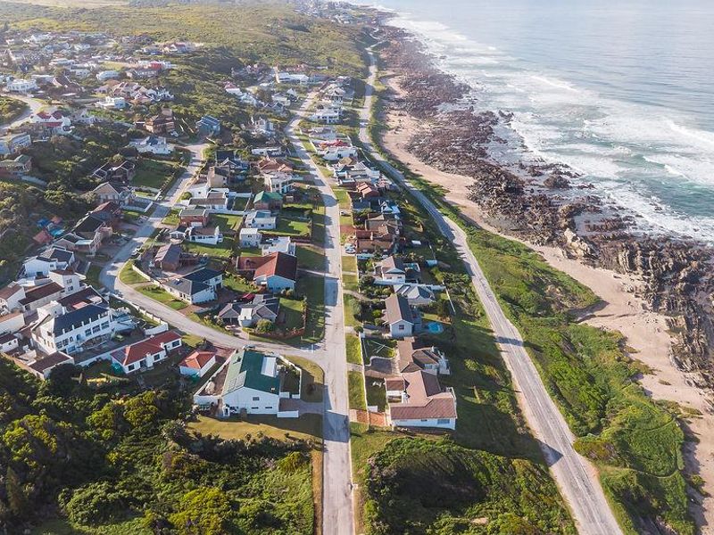 An aerial view of a coastal residential neighborhood situated along the shoreline, showcasing the proximity of the homes to the ocean.