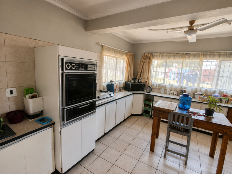 A functional kitchen featuring built-in oven, cooktop, tiled flooring, and ample counter space, offering potential for modernization and aesthetic updates.