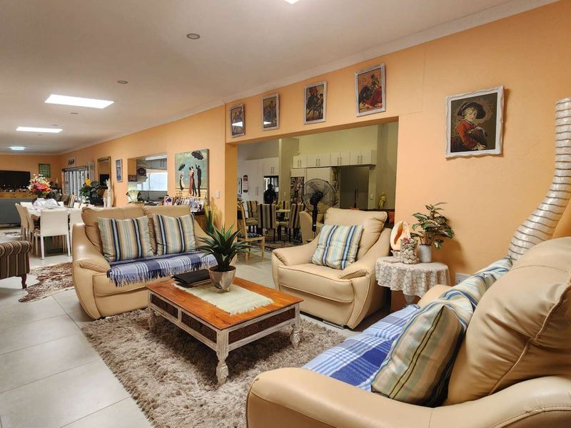 Spacious open-plan living and dining area featuring neutral tiled flooring and recessed lighting, connecting seamlessly to the kitchen space.